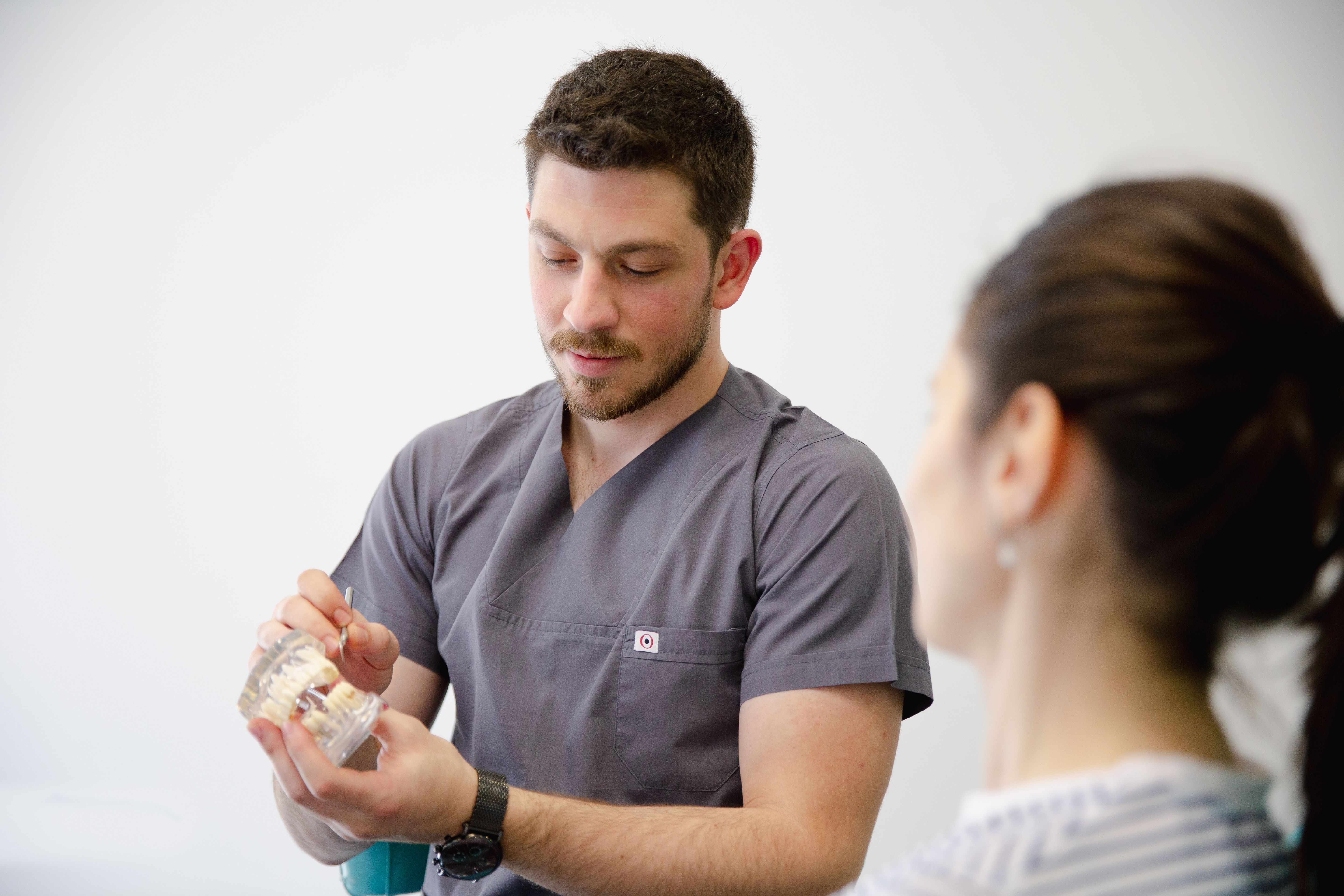 Dentist explaining dental model to a woman in a consultation setting.